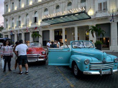 De vieilles voitures de luxe américaines devant l'entrée de l'hôtel Gran Manzana à Cuba, le 11 février 2019 - Yamil LAGE [AFP]