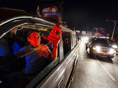 Des personnes utilisent leur téléphone portable sur l'autoroute Francisco Fajardo où ils ont du réseau le 9 mars 2019, pendant la panne d'électricité qui frappe le Venezuela - Matias DELACROIX [AFP]
