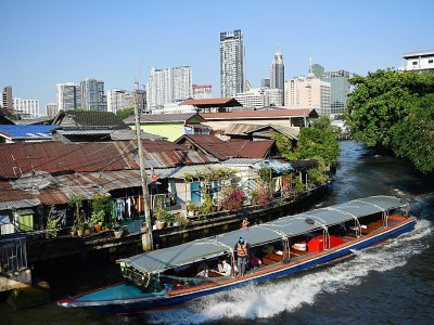 Une navette fluviale longe un quartier pauvre de Bangkok, tout près de buildings modernes, le 13 mars 2019 - Lillian SUWANRUMPHA [AFP]