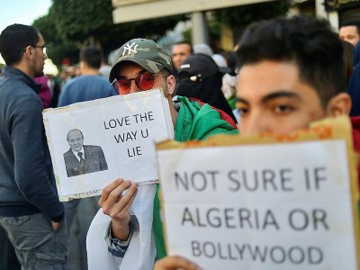 Des manifestants contre le pouvoir brandissent les messages sarcastiques en anglais "J'aime la manière dont tu mens" et "Je ne sais pas si c'est l'Algérie ou Bollywood", le 12 mars 2019 à Alger - RYAD KRAMDI [AFP]