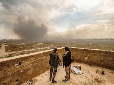 Des membres des Forces démocratiques syriennes (FDS) observent les panaches de fumée après des bombardements sur le dernier réduit du groupe jihadiste Etat islamique (EI) à Baghouz, en Syrie, le 13 mars 2019 - Delil souleiman [AFP]