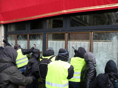 Des "gilets jaunes" s'attaquant à la vitrine du Fouquet's sur les Champs-Elysées, à Paris le 16 mars 2019 - Zakaria ABDELKAFI [AFP]