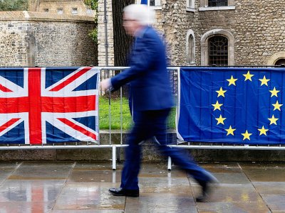 Un Londonien passe devant les drapeaux du Royaume-Uni et de l'Union européenne, près du parlement britannique, le 18 mars 2019 - Niklas HALLE'N [AFP]