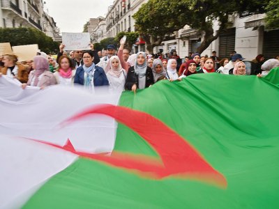 Des Algériens arborent un géant drapeau national lors d'une manifestation contre le président Abdelaziz Bouteflika, le 19 mars 2019 à Alger - RYAD KRAMDI [AFP]