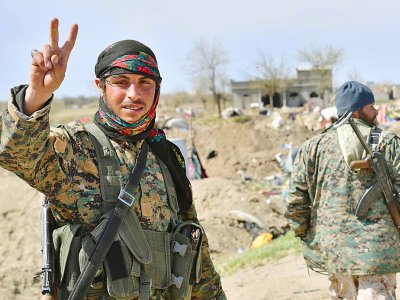 Un combattant des Forces démocratiques syriennes (FDS) fait le V de la victoire le 23 mars 2019 près du champ pétrolier d'Al-Omar, dans l'est de la Syrie, après l'annonce de la chute du "califat" du groupe Etat islamique (EI) - GIUSEPPE CACACE [AFP]