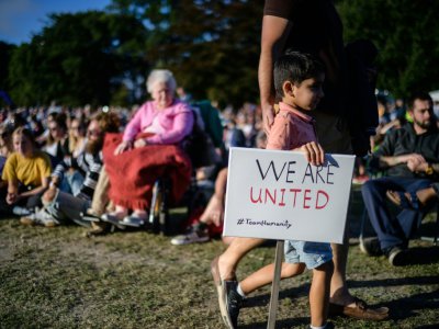 Un petit garçon tient une pancarte "nous sommes unis" lors d'un rassemblement en mémoire des victimes des attaques contre les mosquées de Christchurch, le 24 mars 2019 dans cette ville néo-zélandaise - Anthony WALLACE [AFP]