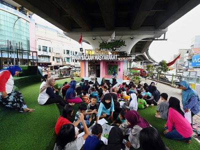Des dizaines d'enfants assistent aux activités après l'école organisées par une bibliothèque de rue installée sous une voie rapide, le 10 février 2019 à Jakarta, en Indonésie - ADEK BERRY [AFP]