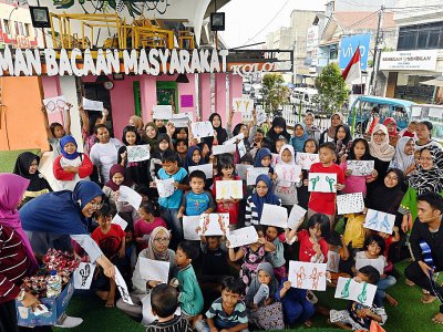 Les enfants montrent leurs dessins à la bibliothèque de rue de Kolong, le 10 février 2019 à Jakarta, en Indonésie - ADEK BERRY [AFP]