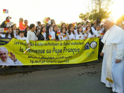 Des enfants des écoles catholiques accueillent le pape François à son arrivée à Rabat, le 30 mars 2019 au Maroc - Handout [Service de presse du Vatican/AFP]