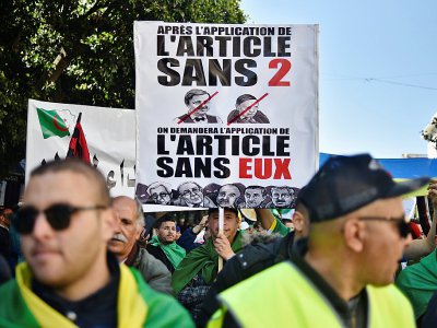 Des manifestants brandissent des pancartes contre des figures emblématiques du gouvernement d'Abdelaziz Bouteflika, à Alger, le 29 mars 2019 - RYAD KRAMDI [AFP]
