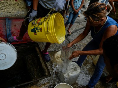 Des habitants du quartier de Petare remplissent des bidons d'eau pour l'utiliser dans leurs toilettes, le 1er avril 2019 à Caracas, au Venezuela - Federico Parra [AFP]