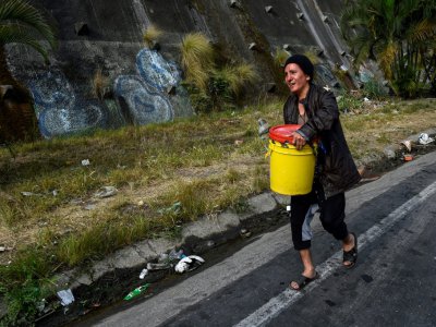 Une femme porte un seau rempli d'eau pour l'utiliser dans ses toilettes, le 1er avril 2019 à Petare, un quartier de Caracas, au Venezuela - FEDERICO PARRA [AFP]