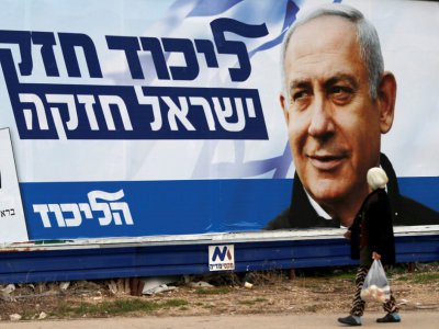 Une arabe israélienne marche devant une affiche électorale montrant le Premier ministre israélien Benjamin Netanyahu, à Haïfa (nord), le 4 avril 2019 - AHMAD GHARABLI [AFP]