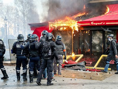 Les forces de l'ordre devant le Fouquet's incendié pendant la manifestation des "gilets jaunes" sur les Champs Elysées à Paris, le 16 mars 2019 - Zakaria ABDELKAFI [AFP/Archives]