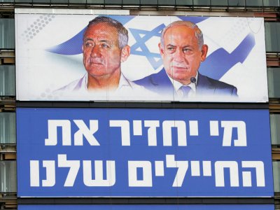 Une affiche électorale montre à Tel-Aviv le 29 mars 2019 les portraits du général Benny Gantz (à gauche) et du Premier ministre Benjamin Netanyahu (à droite), rivaux pour les prochaines élections législatives, tandis qu'en-dessous est inscrit "Qui ra - JACK GUEZ [AFP/Archives]