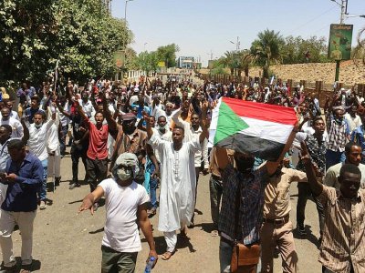 Des manifestants soudanais brandissent le drapeau du Soudan en marchant vers le QG de l'armée à Khartoum, le 8 avril 2019 - STRINGER [AFP]