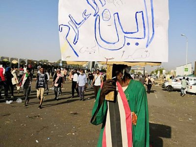 Un manifestant soudanais brandit une pancarte sur laquelle est écrit "Où est la presse, merci à l'armée" lors d'un rassemblement devant le QG de l'armée à Khartoum le 9 avril 2019 - STRINGER [AFP]