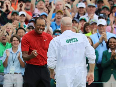 Tiger Woods (g) fête son titre du Masters avec son caddie Joe LaCava (de dos), le 14 avril 2019 à Augusta (Etats-Unis) - DAVID CANNON [GETTY IMAGES NORTH AMERICA/AFP]