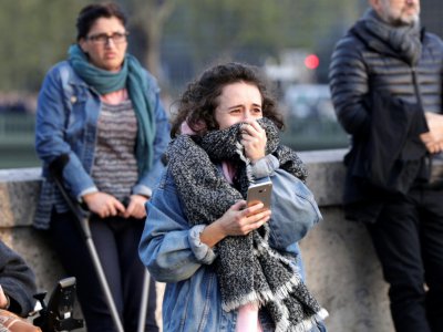 Une jeune femme en larmes devant Notre Dame en flammes, à Paris le 15 avril 2019 - Geoffroy VAN DER HASSELT [AFP]