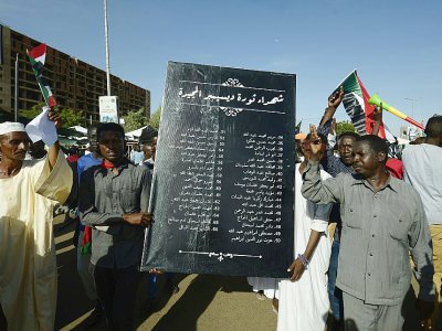 Des manifestants soudanais brandissent une pancarte sur laquelle figure les noms de manifestants tués depuis le début de la contestation, à Khartoum le 15 avril 2019 - Mohammed HEMMEAIDA [AFP]