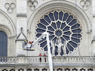 Des pompiers devant l'un des vitraux de la cathédrale Notre Dame de Paris au lendemain de l'incendie qui a ravagé l'édifice, le 16 avril 2019 - Thomas SAMSON [AFP]