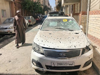 Un homme passe à côté d'une voiture criblée d'éclats le 17 avril 2019 à Tripoli, visée la veille par des tirs de roquettes - Mahmud TURKIA [AFP]