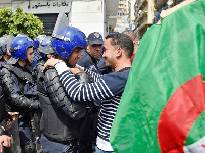 Un manifestant fraternise avec un policier le 23 avril à Alger - RYAD KRAMDI [AFP]