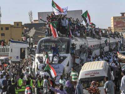 Des manifestants soudanais sur et à proximité d'un train arrivant dans la capitale Khartoum, le 23 avril 2019 - OZAN KOSE [AFP]