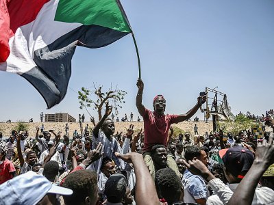 Des manifestants brandissent le drapeau soudanais lors d'un sit-in devant le QG de l'armée à Khartoum, le 22 avril 2019 - OZAN KOSE [AFP]