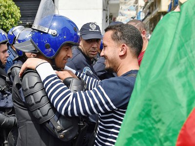 Un Algérien embrasse un agent des forces de l'ordre lors d'une manifestation anti-gouvernementale le 23 avril 2019 à Alger - RYAD KRAMDI [AFP/Archives]