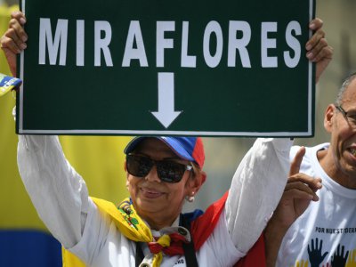 Une partisane de l'opposant vénézuélien Juan Guaido brandit une pancarte portant le nom du palais présidentiel, "Miraflores", à Caracas, le 27 avril 2019 - Federico PARRA [AFP]