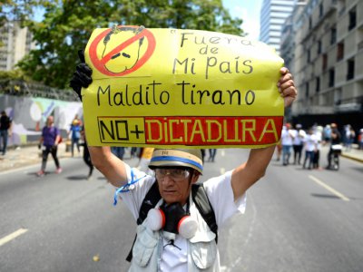 Un manifestant antigouvernemental brandit une pancarte dénonçant la "dictature" du président Maduro, le 1er mai 2019 à Caracas - Matias DELACROIX [AFP]