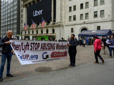 Deux chauffeurs d'Uber manifestent devant le bâtiment de la Bourse de New York à Manhattan. - Don Emmert [AFP]