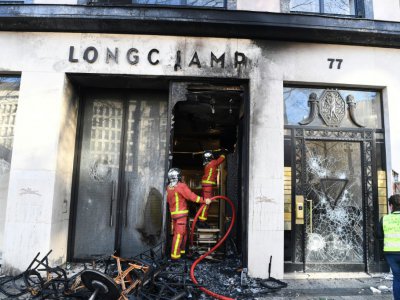 Des pompiers éteignent un incendie dans un magasin Longchamp, lors des manifestations de "gilets jaunes", le 16 mars 2019 sur les Champs-Elysées à Paris - Alain JOCARD [AFP/Archives]