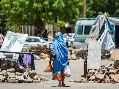 Une Soudanaise passe entre des barricades faites de pierres et de briques près du sit-in organisé par les manifestants soudanais devant le QG de l'armée à Khartoum, le 14 mai 2019 - Mohamed el-Shahed [AFP]
