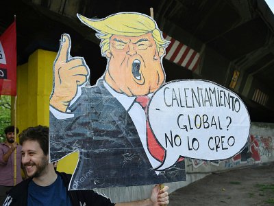 Un homme porte une caricature de Donald Trump disant "Réchauffement global? Je n'y crois pas", le 30 novembre 2018 à Buenos Aires. Le climatoscepticisme du président américain est un modèle pour les certaines Européens - MARTIN BERNETTI [AFP/Archives]