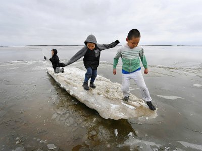 Des enfants jouent sur un morceau de glace près du village eskimau de Yupik, en Alaska (Etats-Unis), le 19 avril 2019 - Mark RALSTON [AFP/Archives]