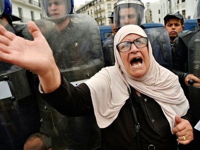 Une manifestante algérienne crie des slogans à côté des forces anti-émeutes à Alger, le 24 mai 2019 - RYAD KRAMDI [AFP]