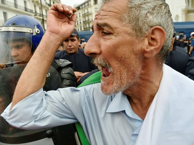 Un manifestant algérien crie des slogans à côté des forces anti-émeutes à Alger, le 24 mai 2019 - RYAD KRAMDI [AFP]