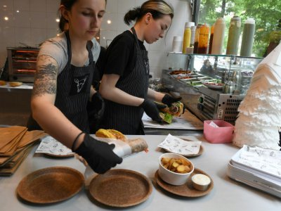Des femmes servent à manger sur des assiettes comestibles dans un restaurant vegan de Varsovie, le 29 mai 2019 - Janek SKARZYNSKI [AFP]