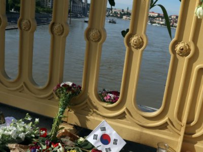 Photo prise le 1er juin 2019 à Budapest, montrant des fleurs, des bougies et un drapeau sud-coréen sur le pont Marguerite qui enjambe le Danube, au-dessus du lieu de la collision entre un bateau de croisière et une embarcation de touristes, qui a fai - FERENC ISZA [AFP]