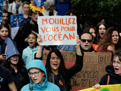 Une manifestante tient une pancarte portant les mots "Mouillez vous pour l'océan" lors de la Journée mondiale de l'océan à Paris, le 8 juin 2019 - Geoffroy VAN DER HASSELT [AFP]
