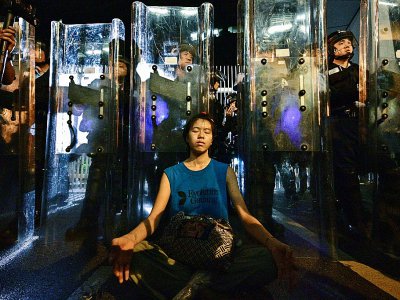 Une femme médite devant les forces de l'ordre, le 12 juin 2019 à Hong Kong - Anthony WALLACE [AFP]