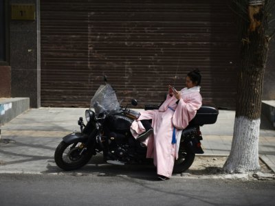 Un homme vêtu d'un "hanfu", un habit traditionnel chinois, assis sur une moto, dans une rue de Pékin, le 5 avril 2019 - GREG BAKER [AFP]