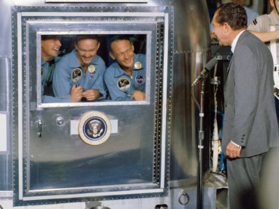 Le président américain Richard Nixon avec les trois astronautes d'Apollo 11, placés en quarantaine à bord du porte-avions USS Hornet, le 24 juillet 1969 - HO [NASA/AFP]