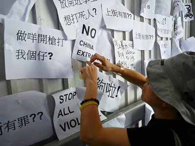 Un homme placarde des slogans dénonçant le projet d'autoriser les extraditions vers la Chine sur un mur près du Conseil législatif à Hong Kong, le 14 juin 2019 - Hector RETAMAL [AFP]