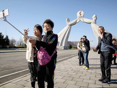 Des touristes chinois se prennent en photo devant un monument à Pyongyang, le 14 avril 2019 en Corée du Nord - Ed JONES [AFP]