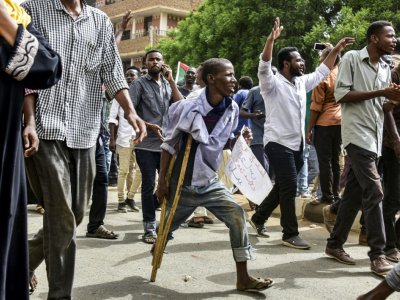 Un manifestant soudanais marchant avec une béquille se joint à une manifestation de masse contre les généraux au pouvoir le 30 juin 2019 à Omdourman, ville voisine de khartoum - Ahmed MUSTAFA [AFP]