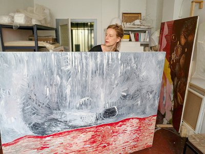 L'artiste allemande Lydia Paasche montre l'un de ses tableaux dans son studio des "Treptow Ateliers", le 20 juin 2019 à Berlin - John MACDOUGALL [AFP]