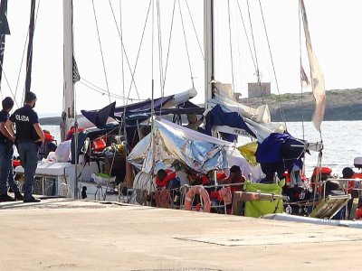 Capture d'écran depuis une vidéo de Local Team, le 6 juillet 2019, montrant des policiers italiens en faction près du navire humanitaire Alex après son arrivée dans le port de l'île de Lampedusa - - [Local Team/AFP]